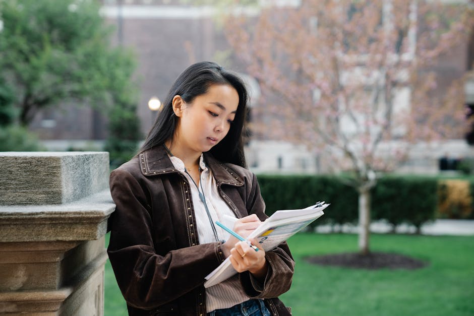 Young woman studying with papers at university campus outdoors.