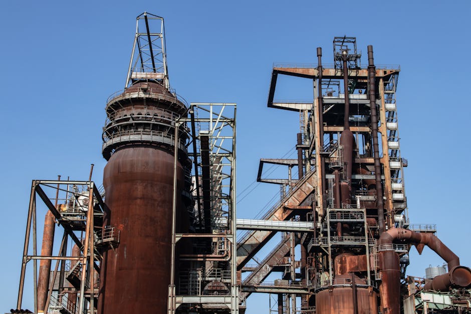 Close-up of a large rusted industrial metal structure with blue sky background.