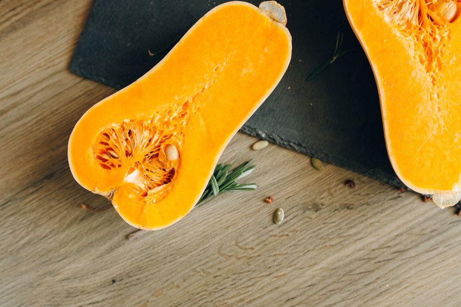 Top view of a sliced butternut squash on a wooden surface, showcasing its vibrant color and seeds.