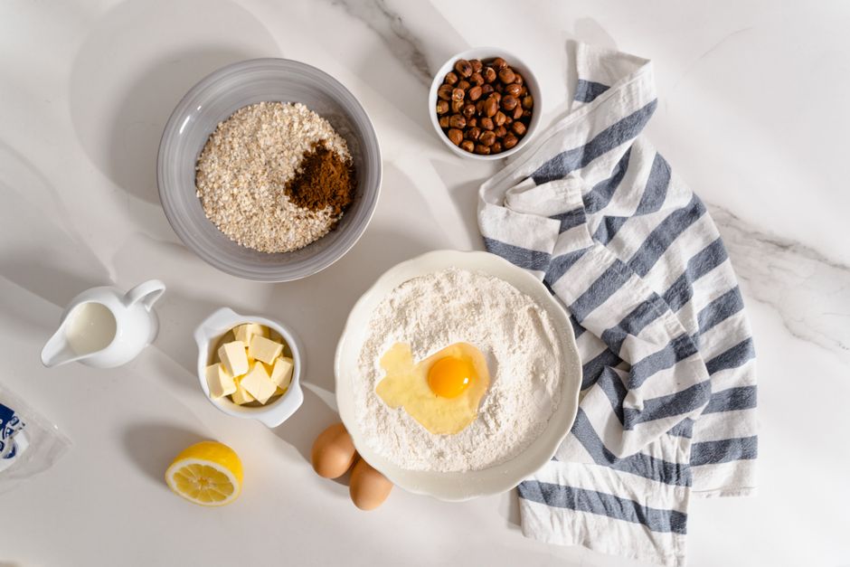 Egg cracked into a bowl of flour with butter and other baking ingredients