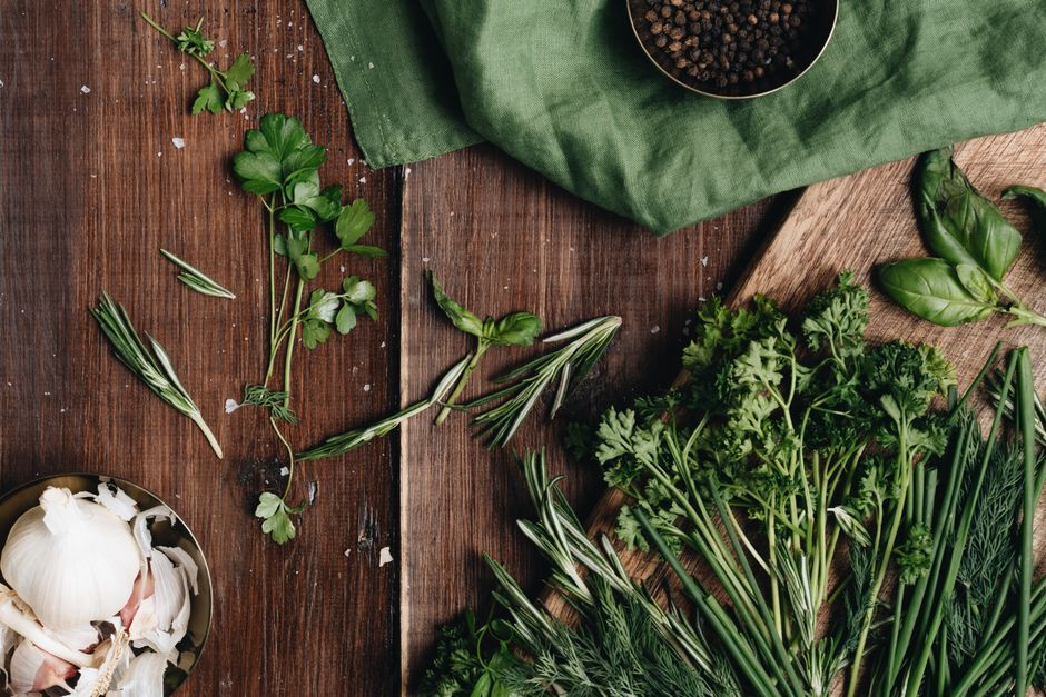 Fresh parsley, chives, basil and rosemary with garlic on a wooden board