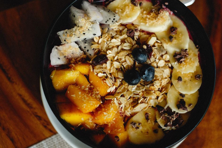 Close-up of a vibrant fruit and granola bowl featuring banana, mango, and dragon fruit slices.