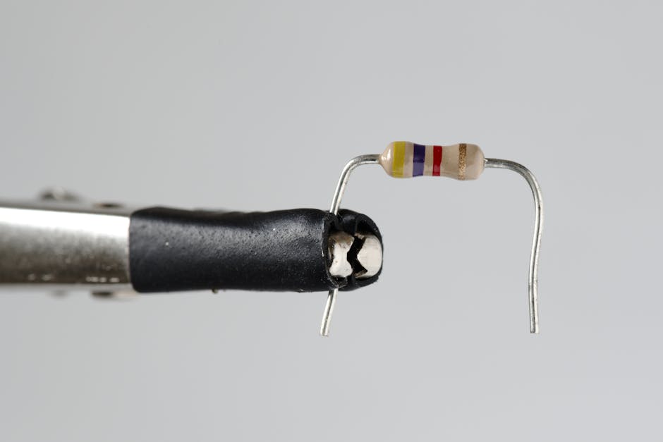 Detailed close-up of a resistor secured by a metallic clamp against a gray background.