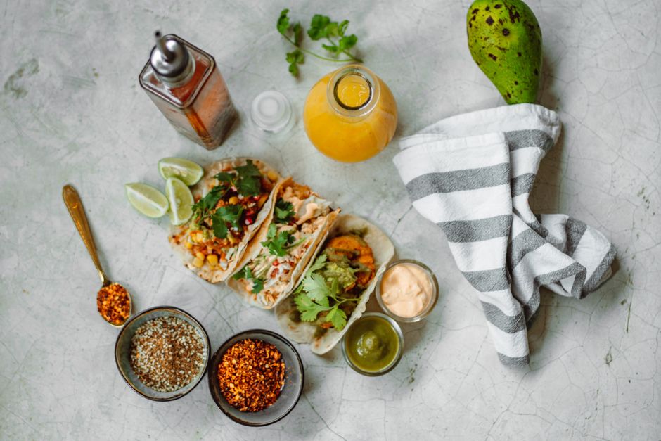 Delicious Mexican tacos with fresh toppings, spices, and juice on a tabletop.