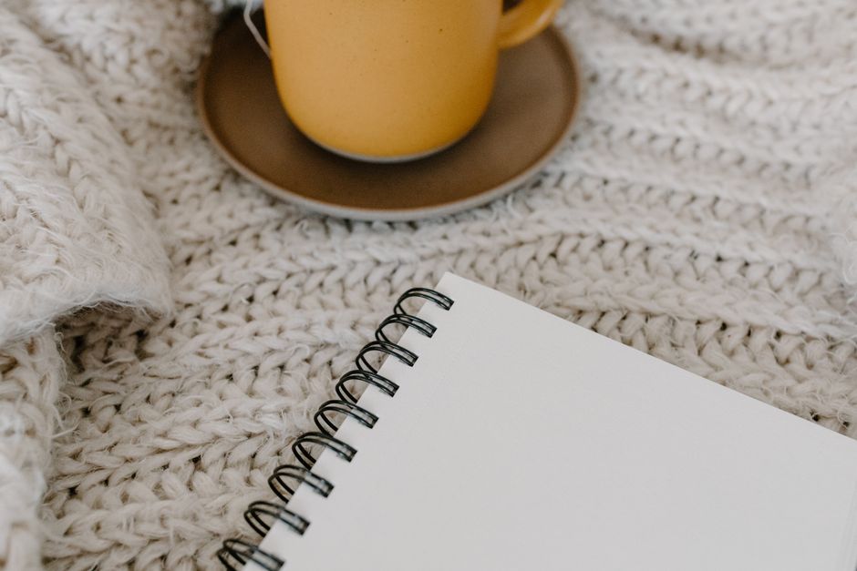 A warm, cozy scene featuring a blank notebook and a mug on a knitted blanket. Perfect for relaxation.