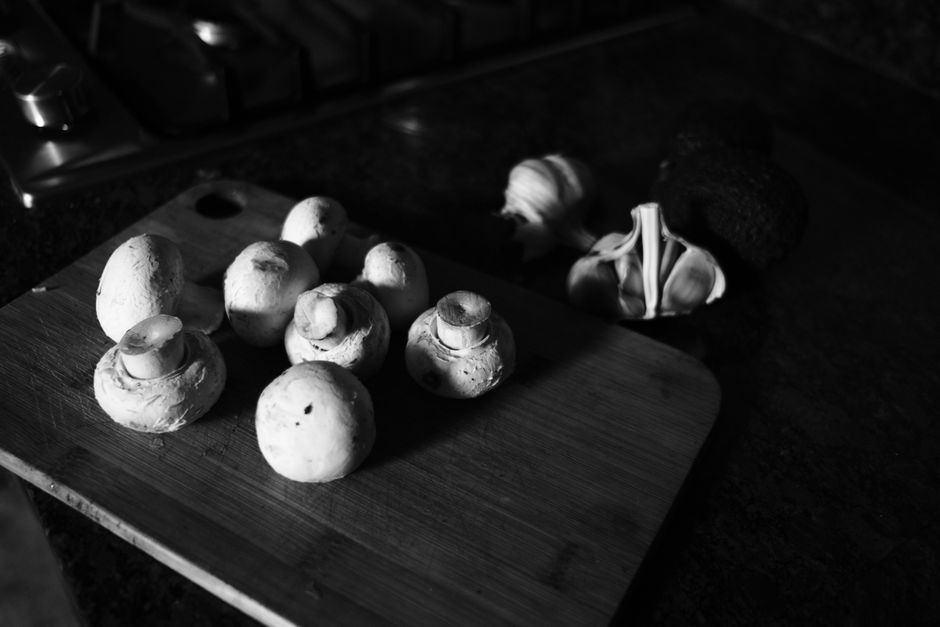 Monochrome image of mushrooms on a wooden cutting board, creating a rustic kitchen scene.